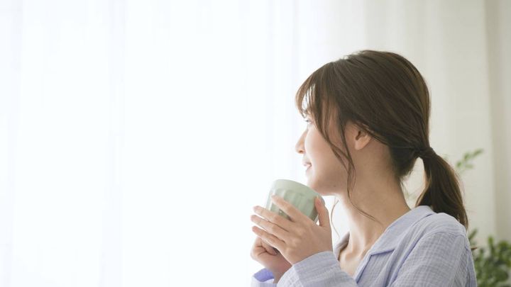 マグカップで飲み物を飲む女性
