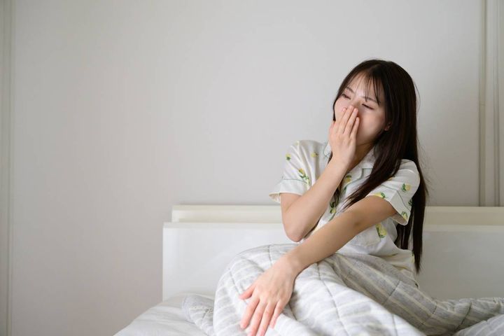 ベッドであくびをする女性