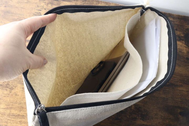 白いクラッチバッグの仕切りにA4書類とスマートフォンが収納されている様子