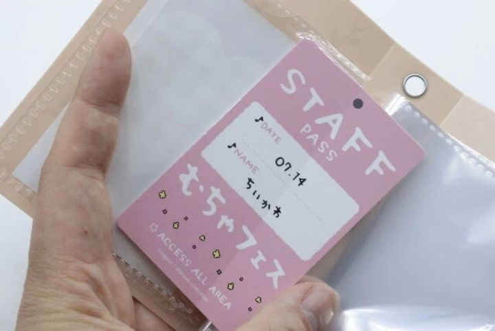 手が透明なポケットに「STAFF PASS」と書かれたカードを入れている