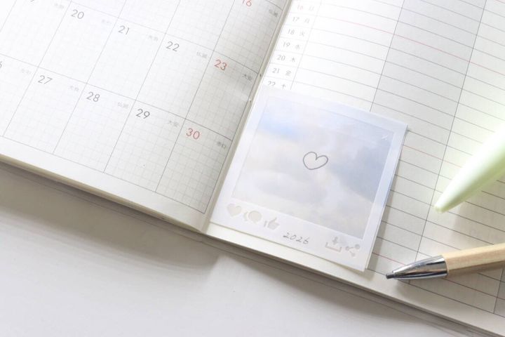 空とSNS風ふせんがスケジュール帳に貼られペンが添えられている