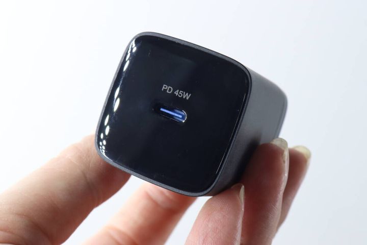 女性の指で持たれた黒いGaN USB充電器本体