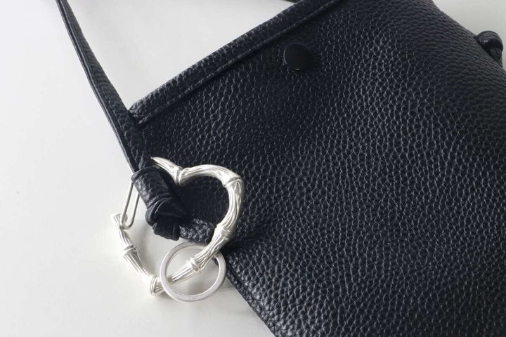黒いバッグの持ち手にハート型シルバーカラビナが付けられている