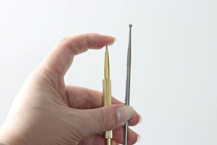 女性の手が金色のポインターと銀色のポインターを比較