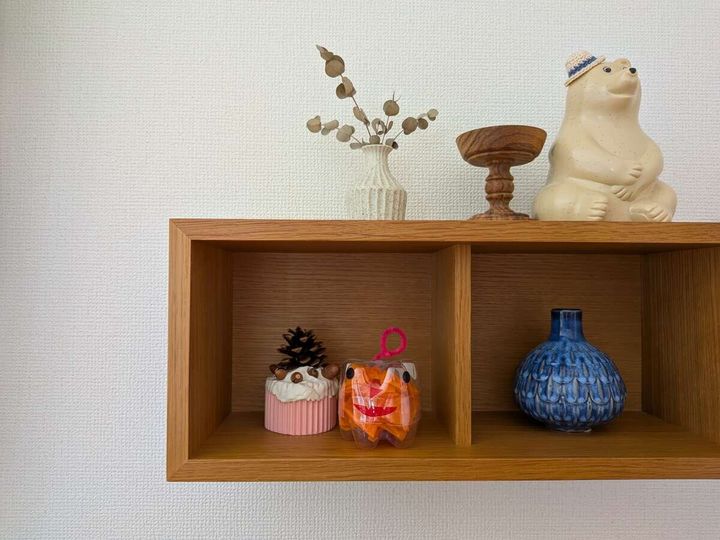 壁に取り付けられた木製棚に飾られた子どもの作品と小物