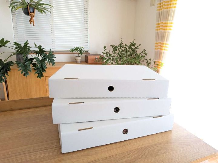 木目のテーブルに積まれた白い思い出の品収納ボックス