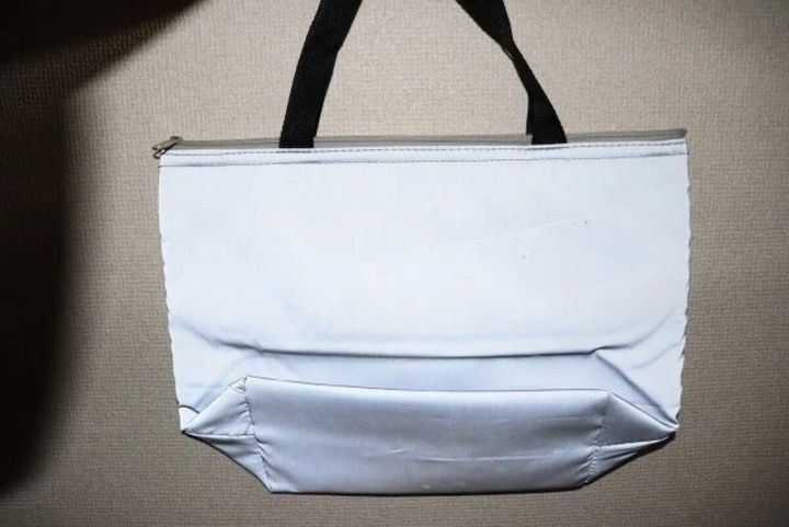 暗い場所で光を反射して輝くグレーの保冷トートバッグ。