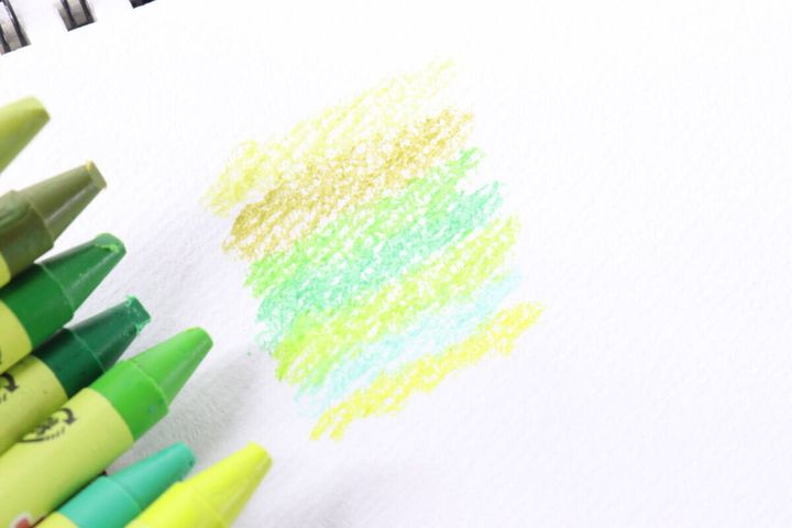 白い紙に緑と黄色のクレヨンで試し書きされた四角い模様