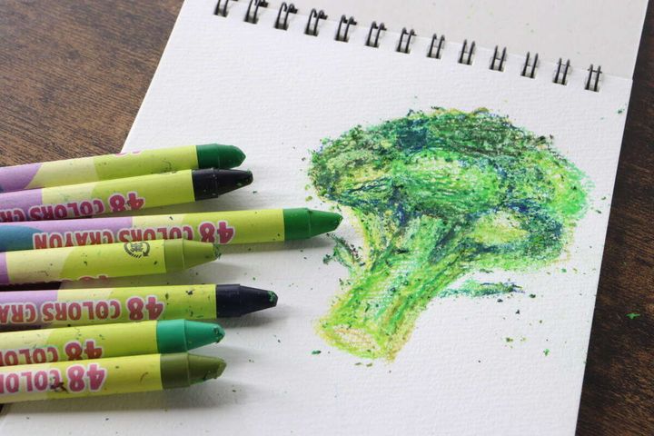 白いスケッチブックに描かれたブロッコリーの絵と緑系のクレヨン