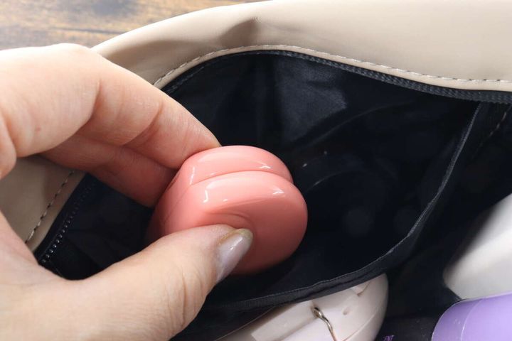 ポーチの仕切りにピンク色のメイクスポンジを入れている手元