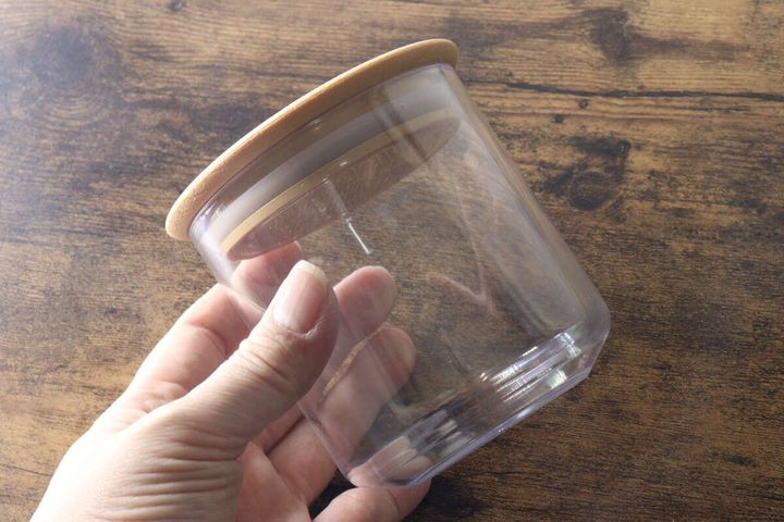 女性の手で持たれた木目調蓋のキャニスター