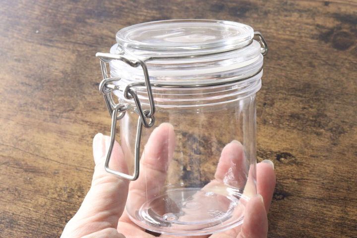 女性の手で持たれた金具付きPET保存容器