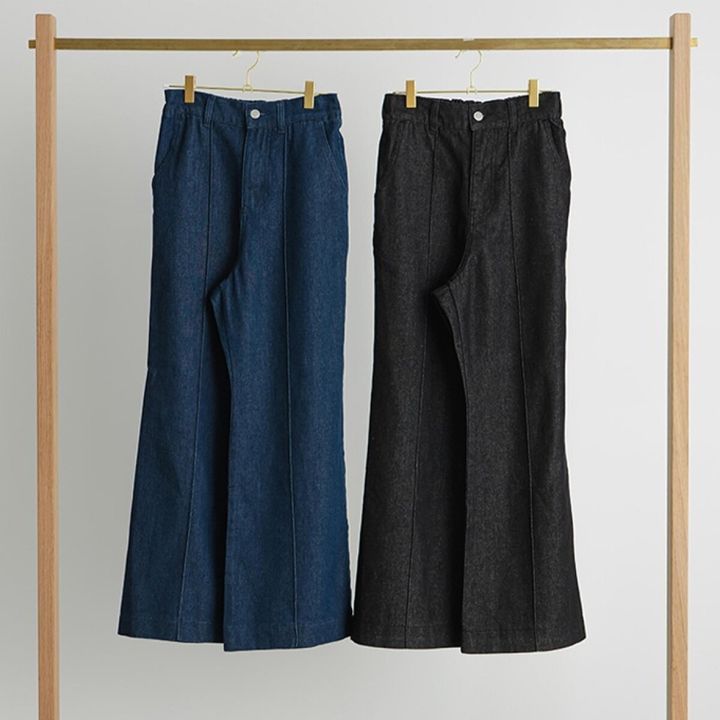 金色のハンガーラックに吊るされた青と黒のフレアデニムパンツ