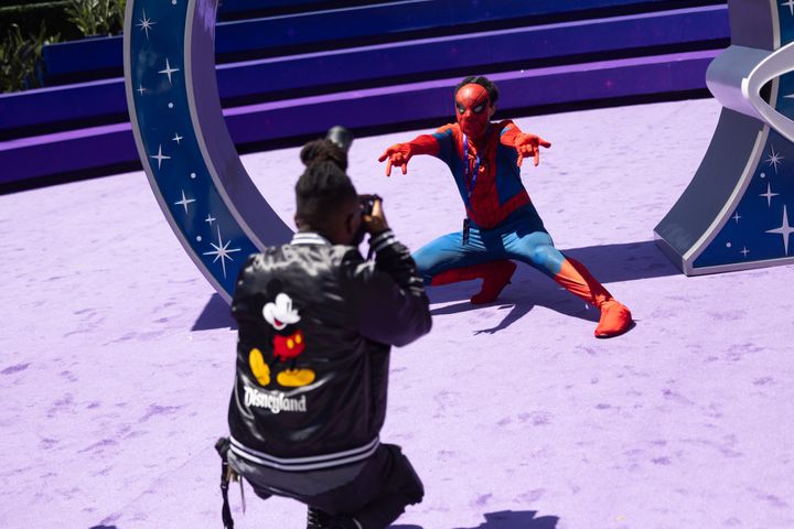 D23サインの前で腕を広げるスパイダーマンと、それを撮影する来場者