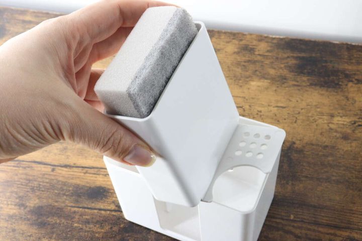 手が白い収納ケースの中央部分に付属のグレーのスポンジを入れている