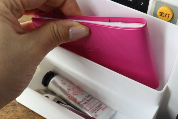 スタンドのポケットにメモ帳とハンドクリームを収納する手