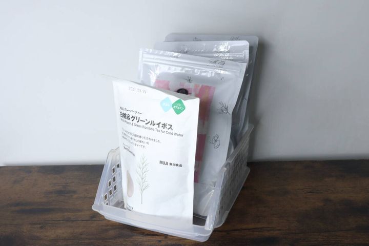 透明な収納ケースに、無印良品のお茶の袋が複数立てて収納されている