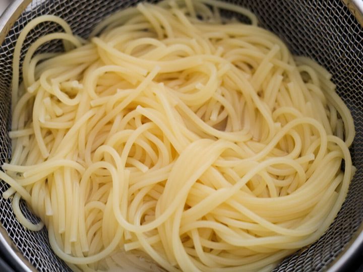 ザルで湯切りされた、茹で上がったばかりのスパゲッティ