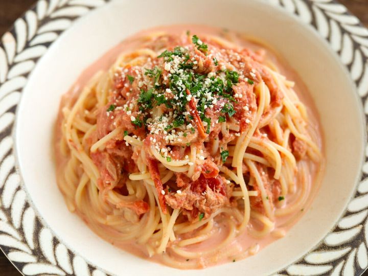 白い深皿に盛り付けられた冷製パスタにパセリと粉チーズがトッピングされている様子