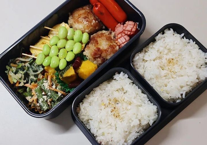 濃いグレーの三分割式弁当箱におかずとご飯がたっぷり詰められている