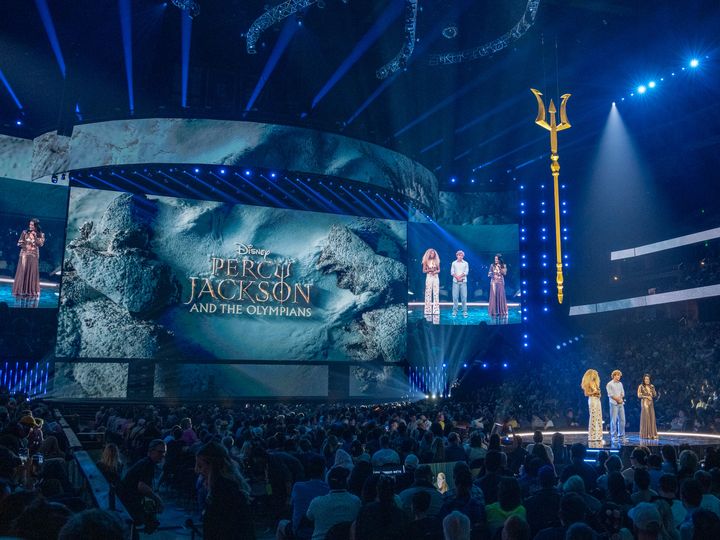 黄金のトライデントが吊るされたステージに並ぶアンドラ・デイ、ウォーカー・スコベル、ミンナ・ウェン