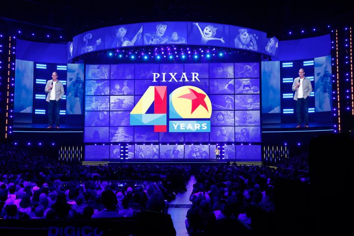 PIXAR 40 YEARSのロゴと歴代作品のキャラクターが並ぶステージに立つピート・ドクター