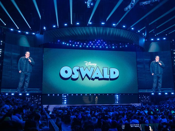 OSWALDのロゴが映し出されたステージで語るジョン・ファヴロー