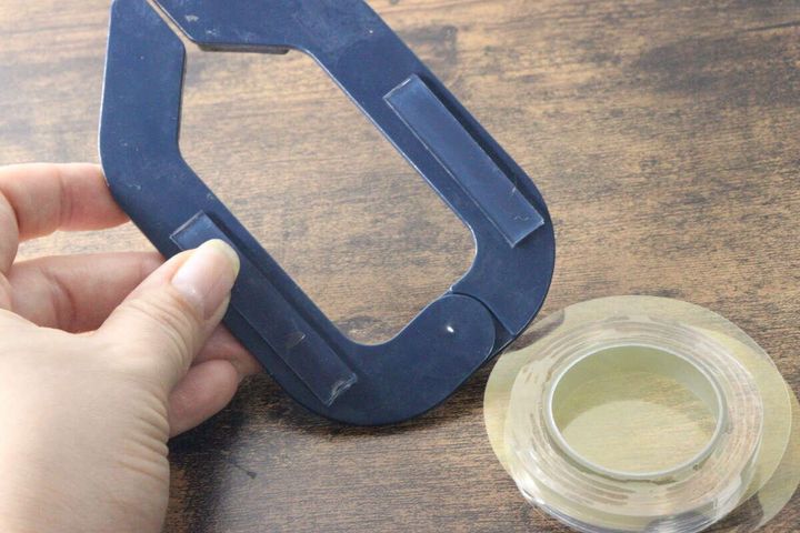 指で持った青いクリップに強力両面粘着ゲルテープを貼り付けている