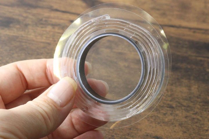 指で持った透明な強力両面粘着ゲルテープのロール
