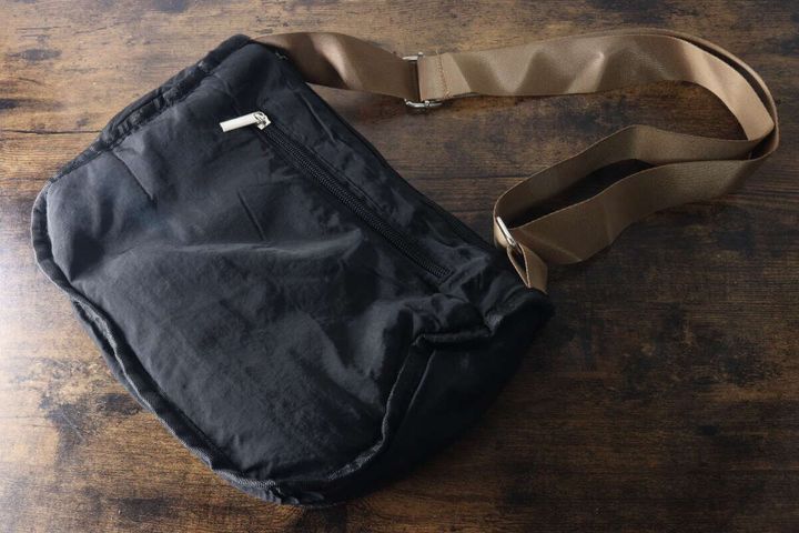 黒いナイロンバッグの背面にあるファスナーポケットと伸びるストラップ