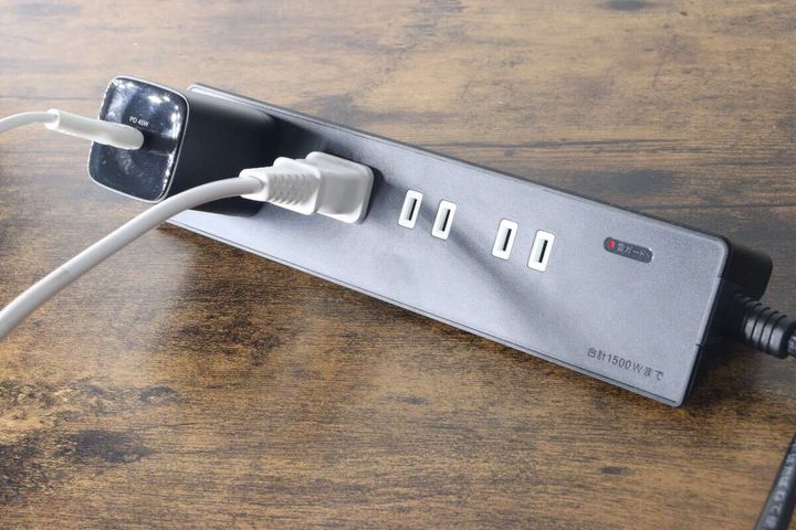 黒いテーブルタップに白い充電器とプラグを挿している