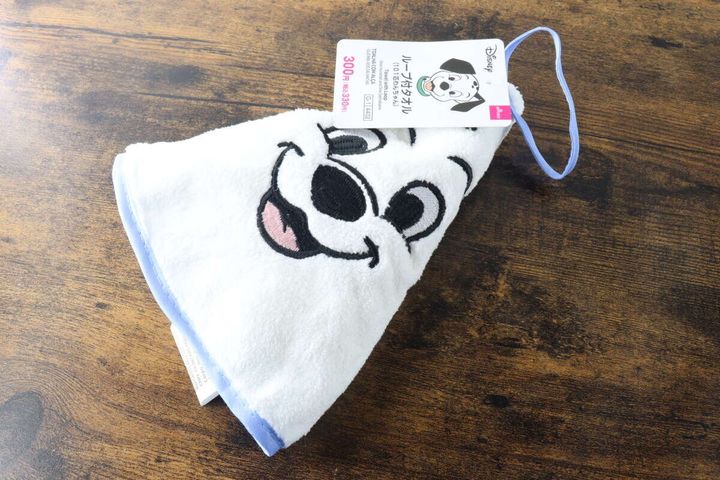 白い101匹わんちゃんの顔が刺繍されたループタオルが畳まれ木目のテーブルに斜めに置かれている