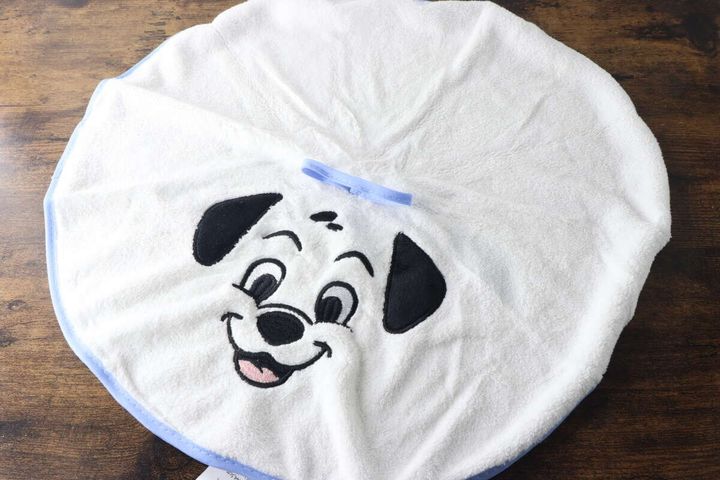 白い101匹わんちゃんの顔が刺繍されたループタオルが円形に広げられ木目のテーブルに置かれている