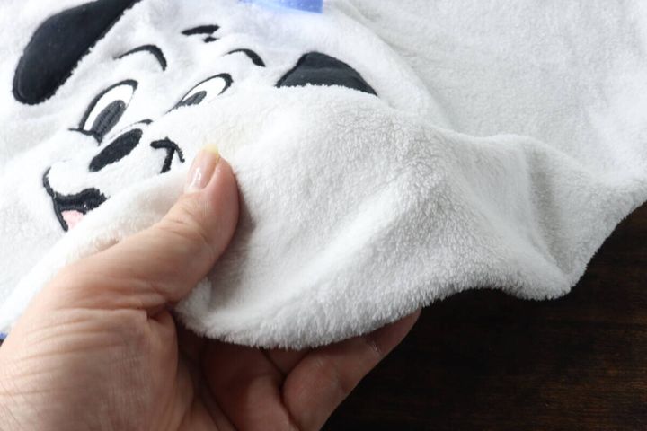 白い101匹わんちゃんループタオルのふわふわした生地を指でつまんで質感を見せている
