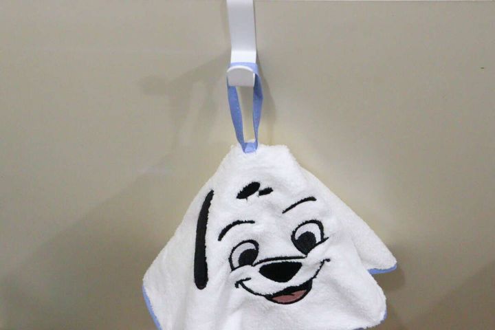 白い101匹わんちゃんの顔が刺繍されたループタオルが白いフックに吊り下げられている