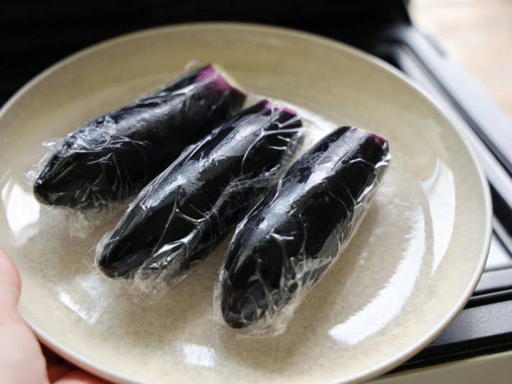 ラップで包まれたなす3本が白い耐熱皿に乗っている