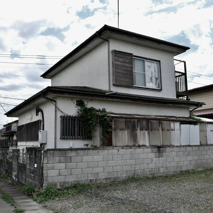 住宅街に建つ、二階の窓が見える古い一軒家の外観