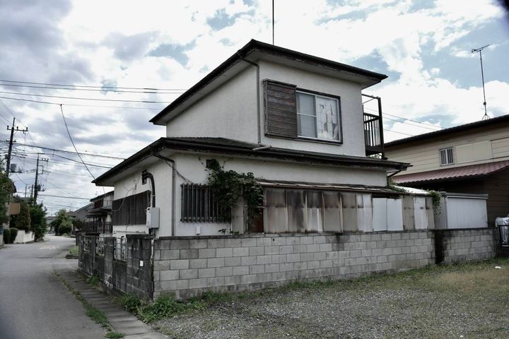 住宅街に建つ、二階の窓が見える古い一軒家の外観