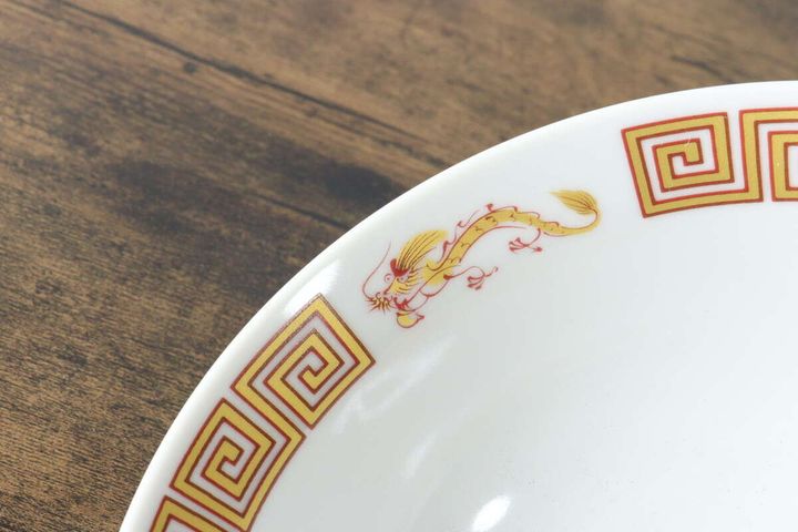 ラーメン丼の縁に描かれた、金色の龍と赤い幾何学模様のアップ