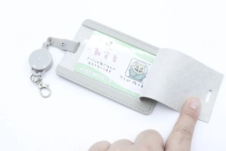グレーのパスケースのカバーを指で開け、中のカードが見えている状態