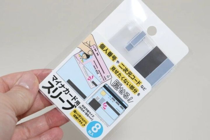 手で持たれたマイナカード用スリーブのパッケージ。イラストで使い方を説明