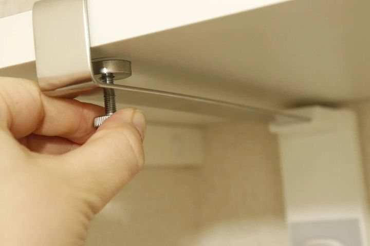 吊り戸棚の底板にキッチンペーパーホルダーをネジで固定する手元