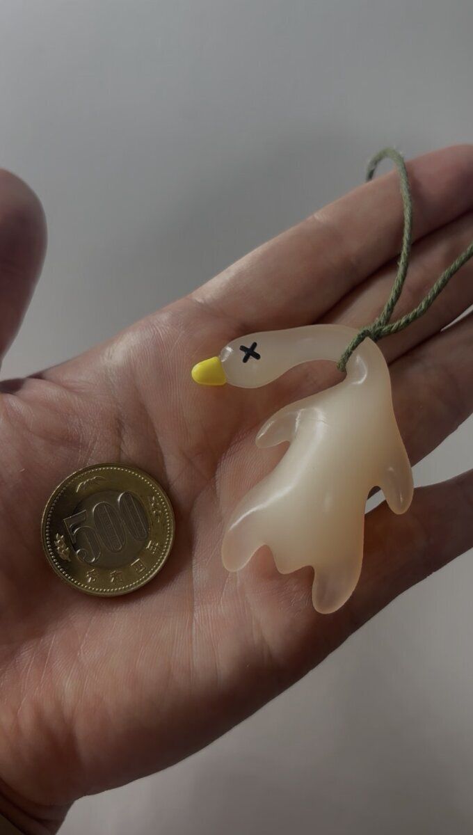 手のひらに乗せられたアヒル型紫外線チェッカーと500円玉の比較