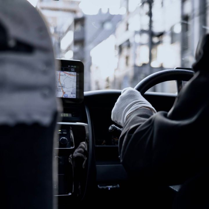 タクシーの車内から見た運転席と、ハンドルを握る運転手。