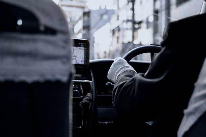 タクシーの車内から見た運転席と、ハンドルを握る運転手。
