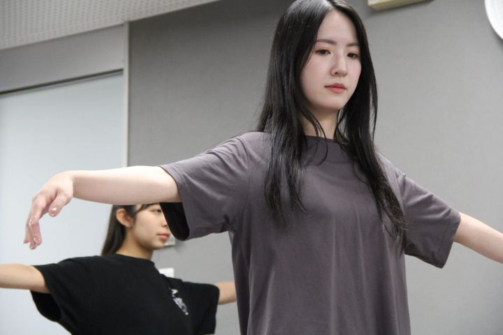 稽古場で腕を左右に広げる出演者たち