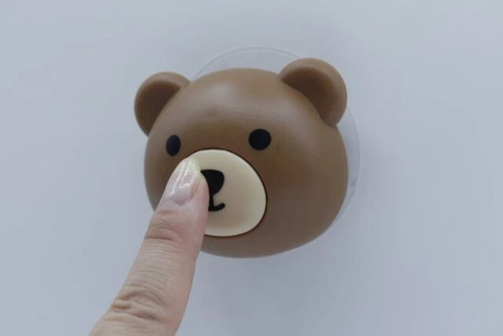 茶色いくまの顔型フックの鼻を指で押している様子