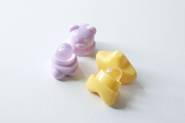薄紫のくま型と黄色の星型のミニリップブラシの蓋が開いている