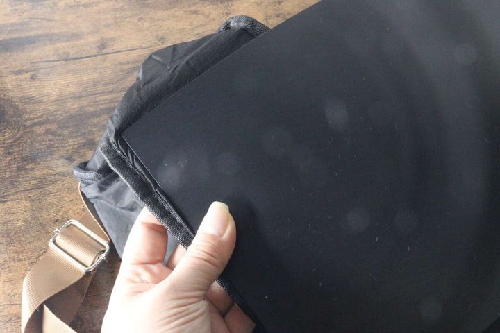 女性の手が黒いショルダーバッグの底にプラ底板を差し込んでいる