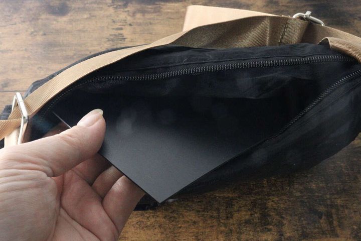 女性の手がカットした黒いプラ底板をバッグの底に入れている